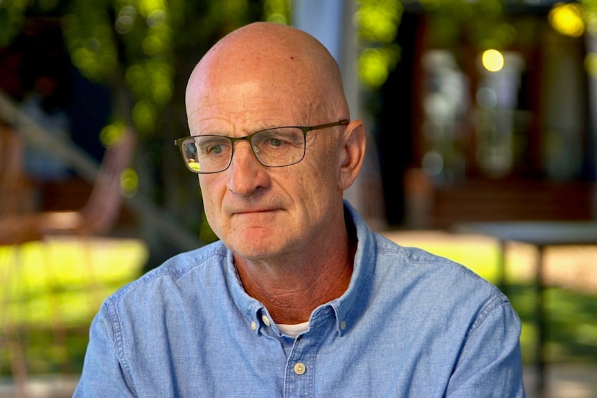 A man wearing glasses and a blue shirt.