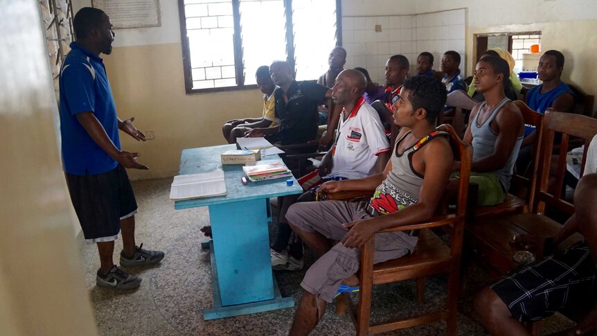 A man stands in front of drug users in a classroom at a "Recovery Community Zanzibar" treatment centre.
