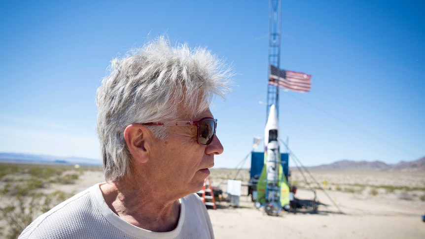 Man looking at his home-made rocket in the Californian desert.
