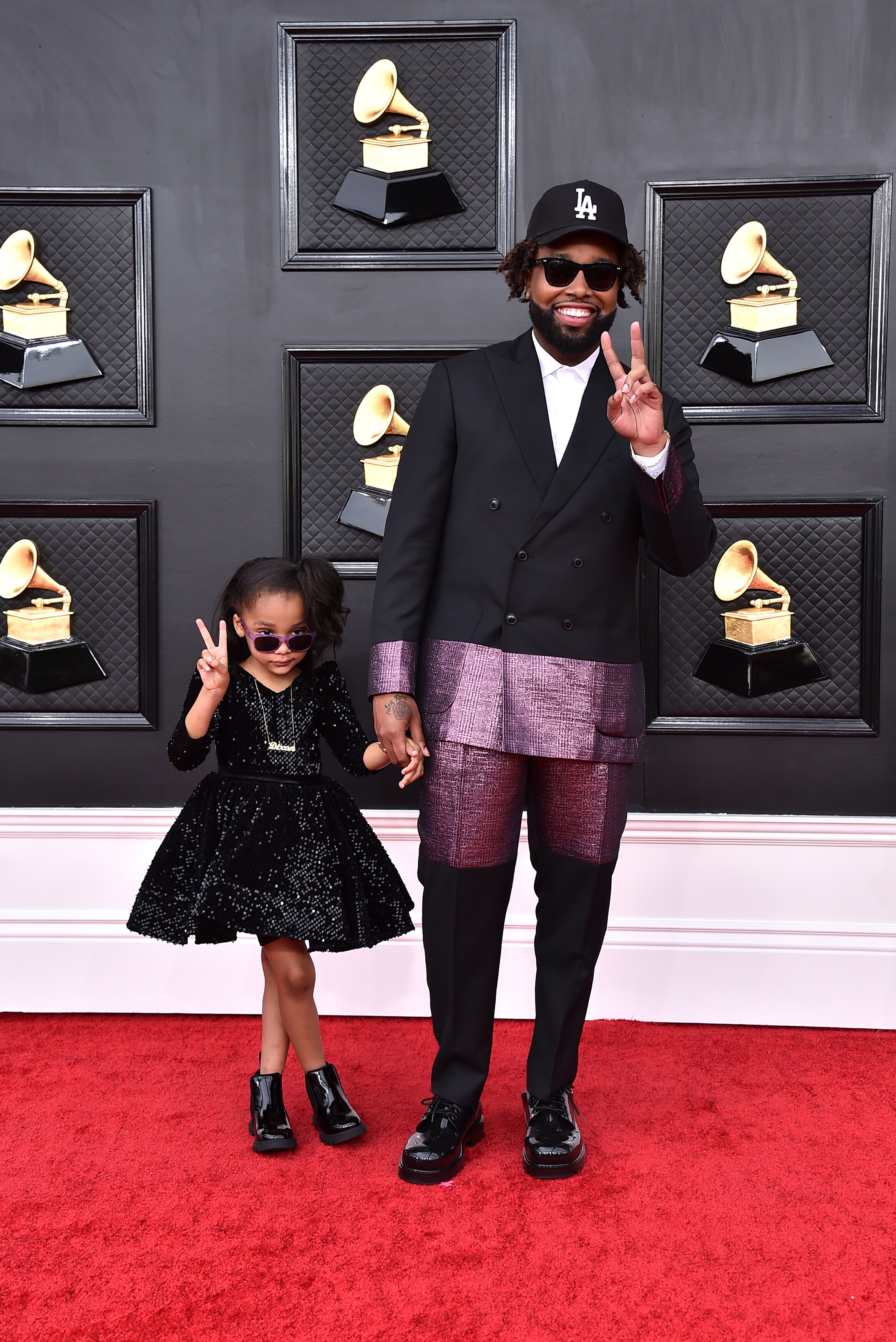 kenyon dixon with his young daughter on the red carpet both holding up peace signs with their fingers