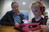 Michelle Joosse sits with her daughter, who is doing homework on an iPad.