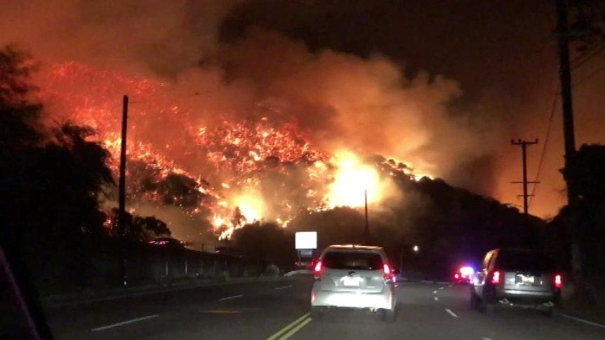 Huge flames engulf a Los Angeles hillside as residents drive only metres away.
