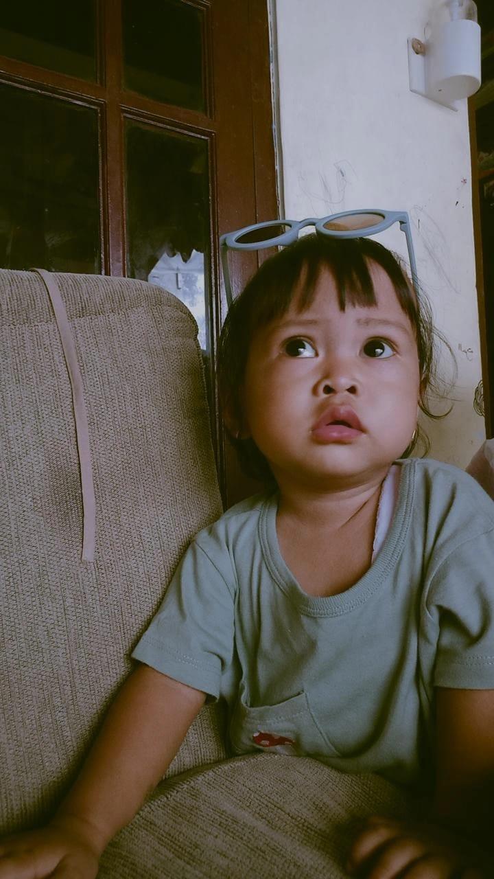 Toddler girl with sunglasses on her head.