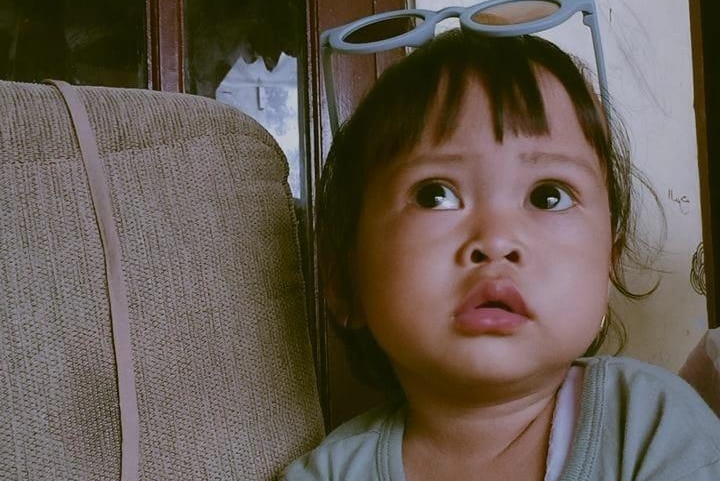 Toddler girl with sunglasses on her head.