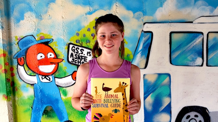Portrait of 13 year-old Lauren Trott holding the book she has published.