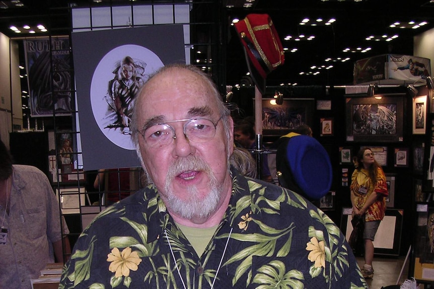 A large bespectacled man in his 50s wears a bright Hawaiian shirt at a gaming convention.