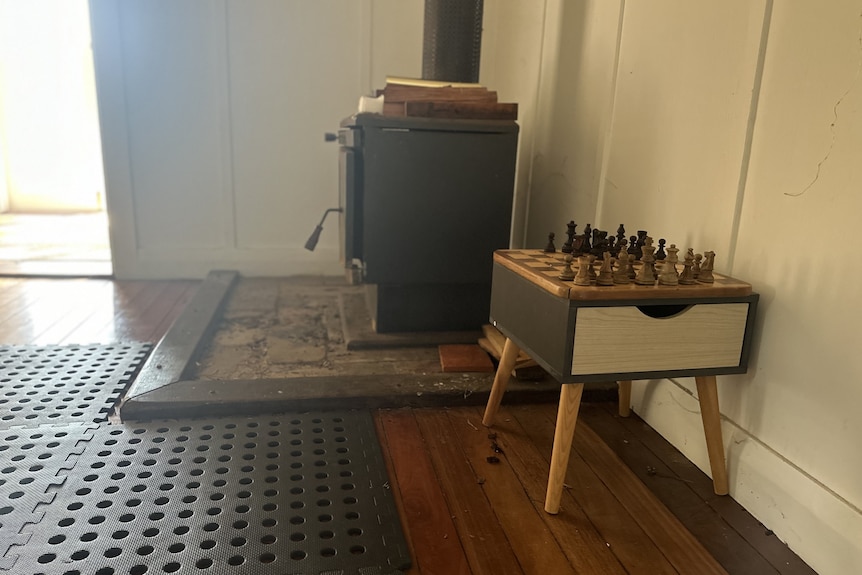 A chess board next to a cast-iron stove in a house.