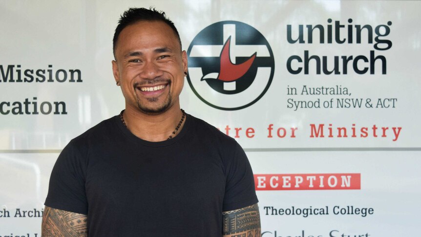 Multicultural Ministry Consultant Reverend Fie Marino stands in front of Uniting Church sign.