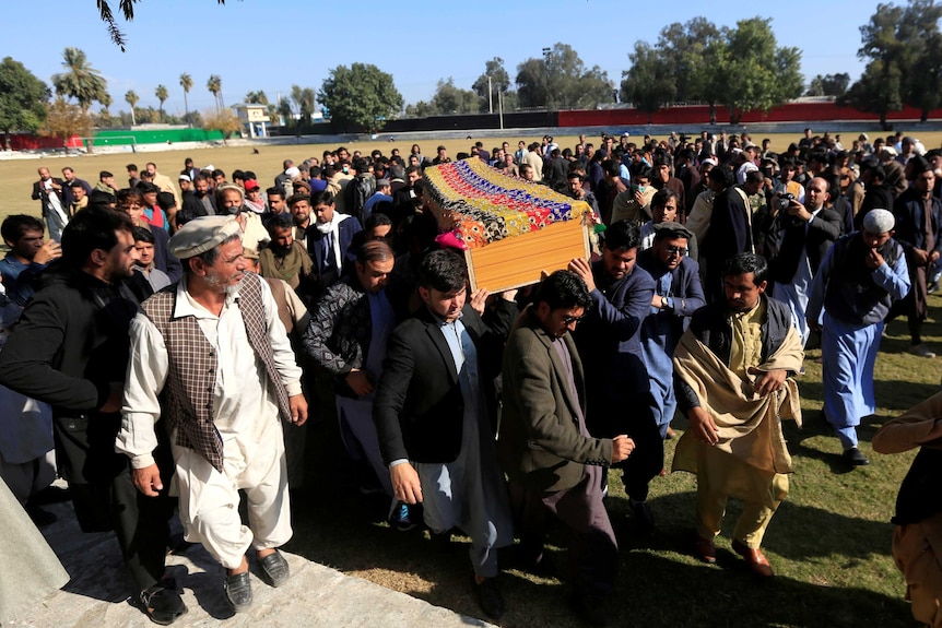 A group of men carry a coffin on their shoulders.