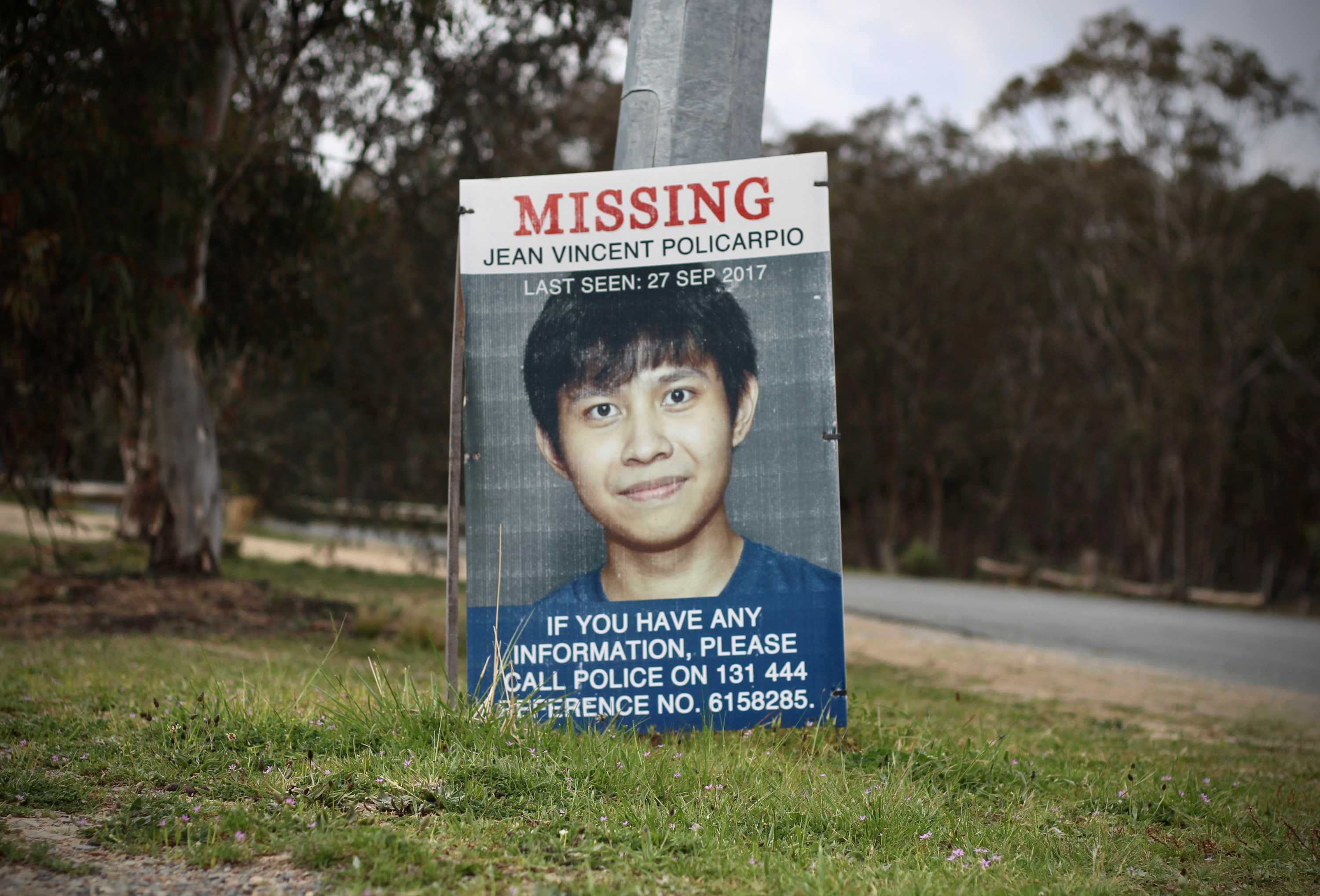 A sign of missing Canberra man Jean Vincent Policarpio sits on the side of the road