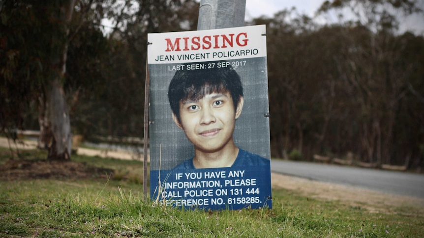 A sign of missing Canberra man Jean Vincent Policarpio sits on the side of the road