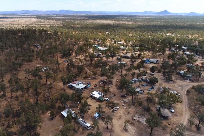 Aerial photo of about a dozen shacks dotted among red dirt roads and scrub
