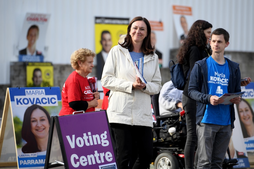 a woman and a young man hand out flyers at a polling booth