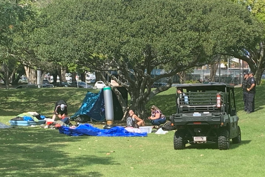 Police and council workers pack up a tent and other material in a homeless camp