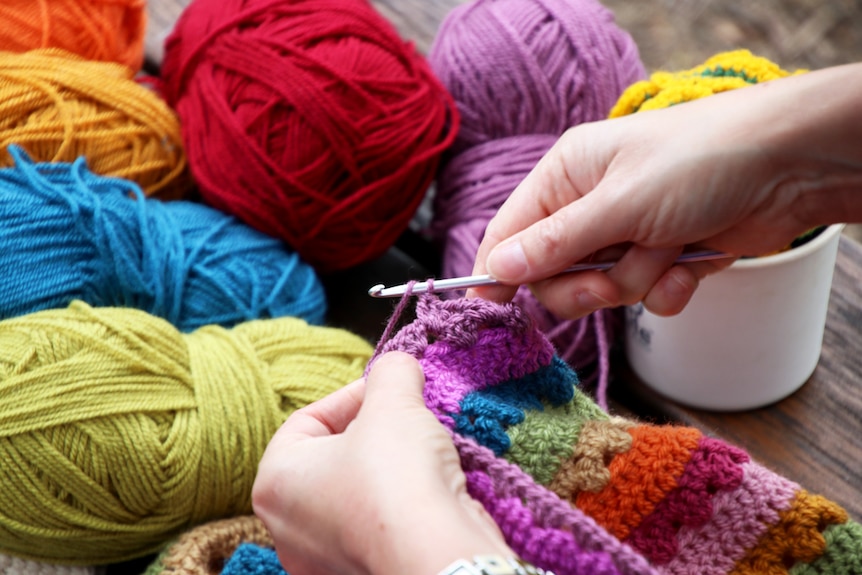 A close up view of Pippa Burns working on some crochet, with wool in the background.
