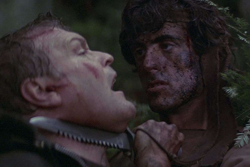 Sylvester Stallone holds a knife to Brian Dennehy's neck in Rambo First Blood.