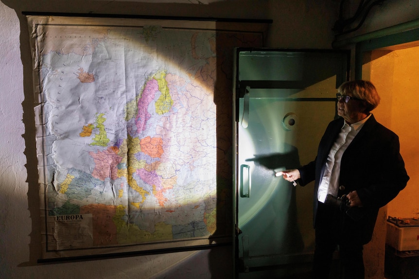 Woman shines torch light on old Soviet Union map on wall.