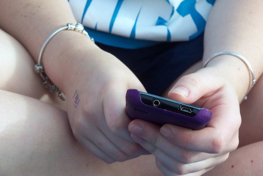 Girl holds mobile phone in her hands.