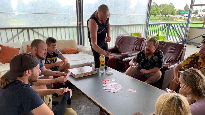 Backpackers playing cards on a table in a hostel.