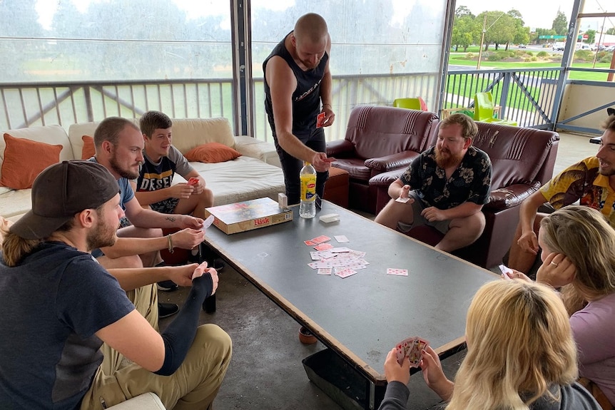 Backpackers playing cards on a table in a hostel.