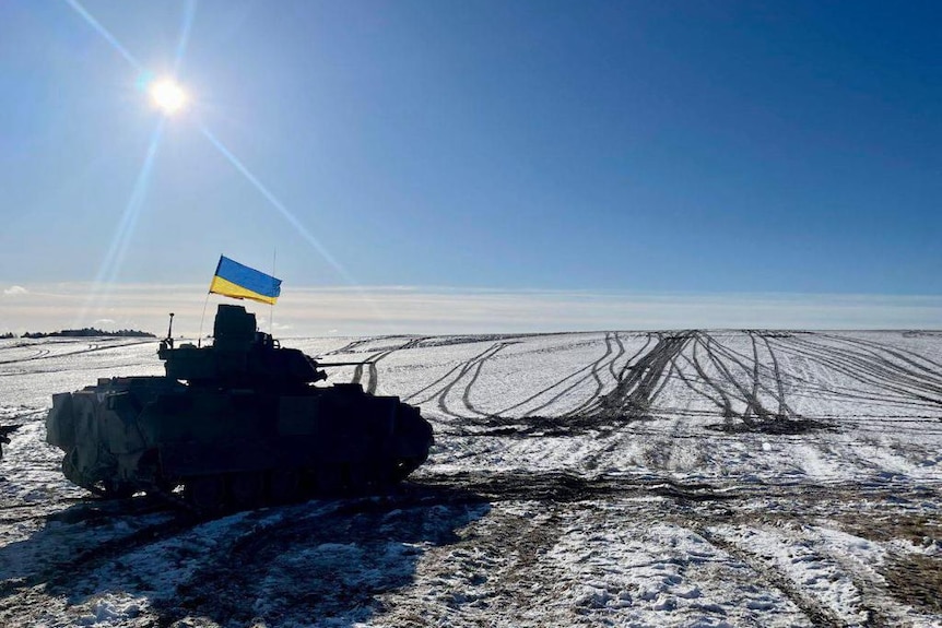 A tank bearing a Ukraine flag on a snowy plain 