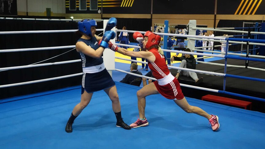 The two boxers throw punches in the ring.