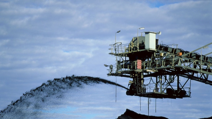 Mine conveyor belt sprays coal in the air into a pile dug from a mine at Oaky Creek near Middlemount in central Qld