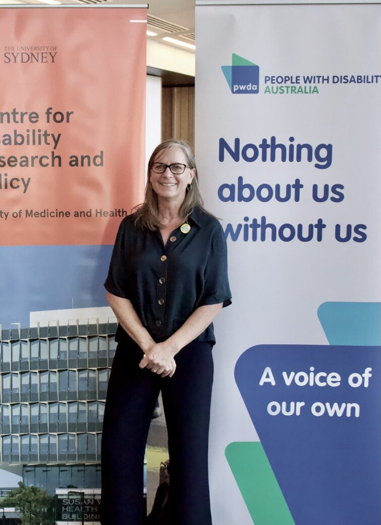 Uma mulher está diante de uma placa que não diz nada sobre nós sem nós