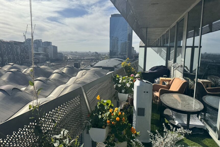 The undulating roof of Southern Cross can be seen adjacent to a balcony with plants.