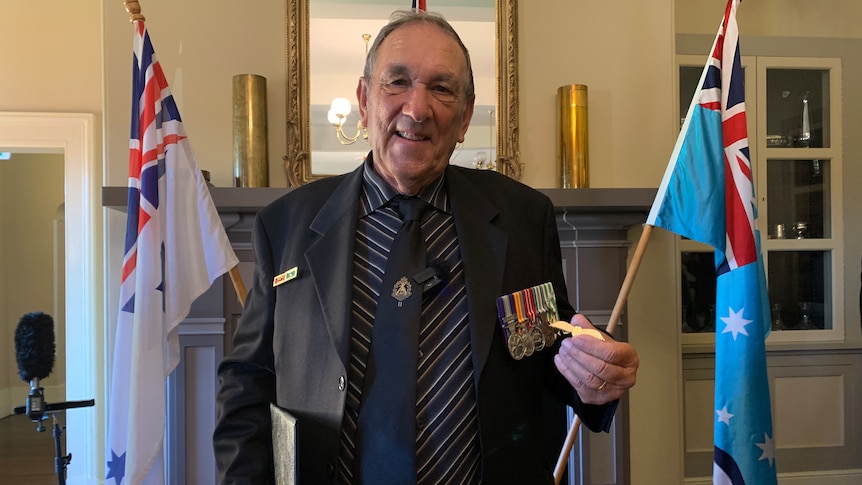 Patrick Halley wears medals and holds his Gunner's Wings medal