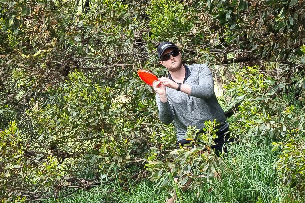 A disc golf player looks to angle a throw out of the trees and back onto the fairway.