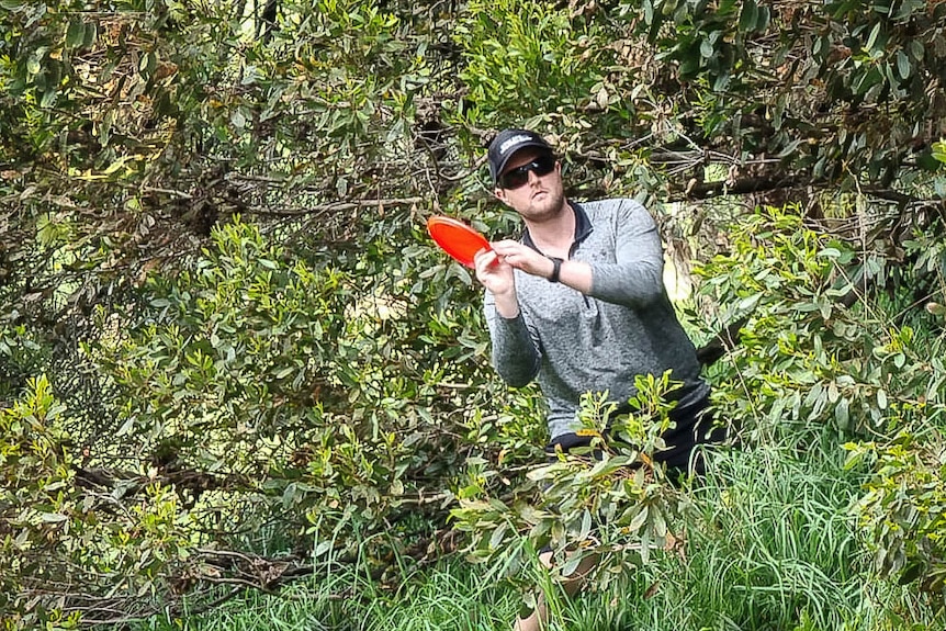 A disc golf player looks to angle a throw out of the trees and back onto the fairway.