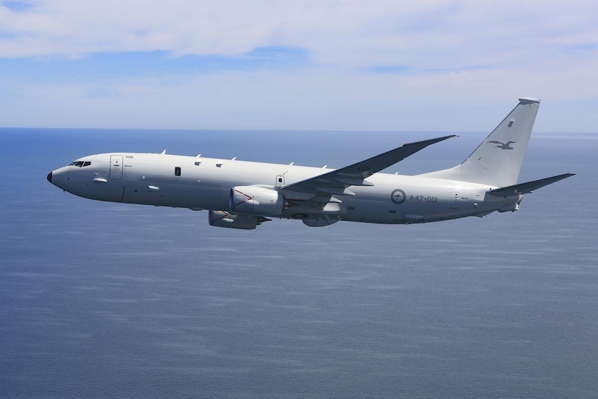a side view of a P-8A Poseidon showing it fly above an ocean at day time 