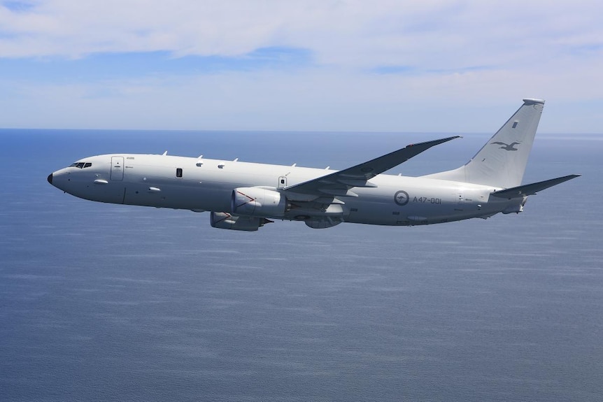 A side view of a P-8A Poseidon showing it fly above an ocean at day time 