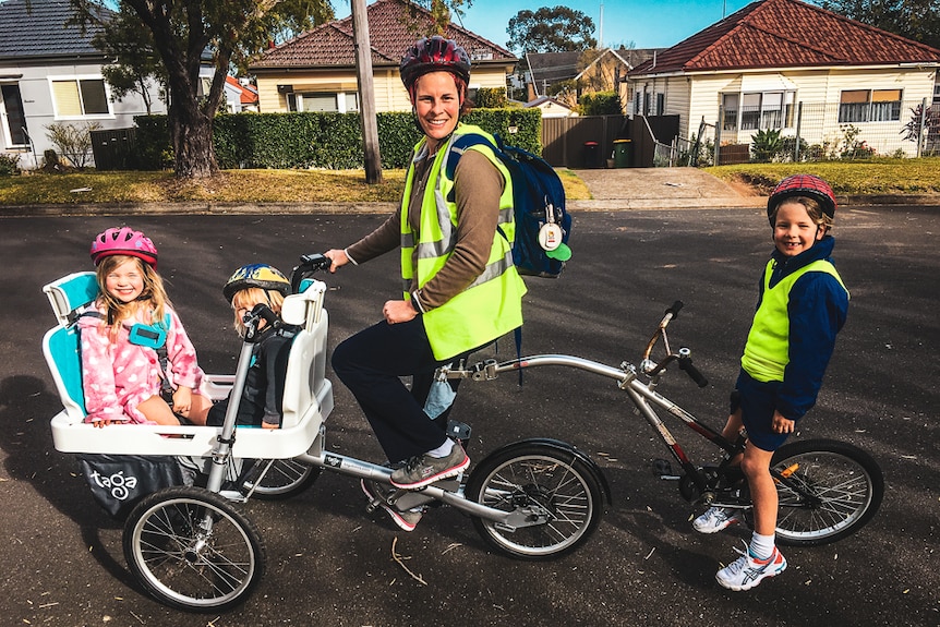 Woman with three children using a tricycle.