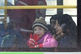 A child waves to photographers as she leaves Aleppo