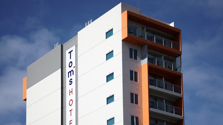 A tall building with orange balconies and the words "Tom's Hotel" on the side