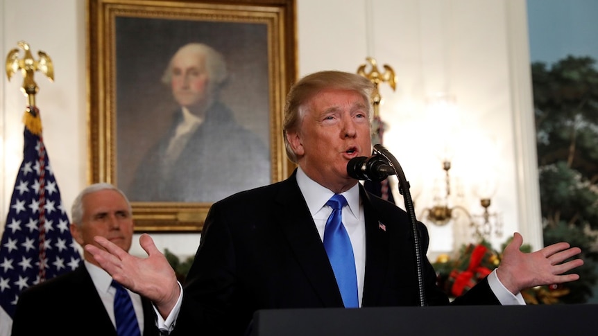 Donald Trump holds out his hands as he speaks into a microphone.