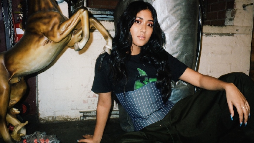 Young woman wearing pinstripe corset over black and green t-shirt, wearing dark pants