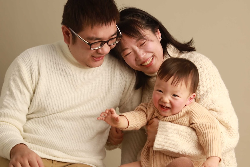 A family siting in a photography studio and laughing happily.