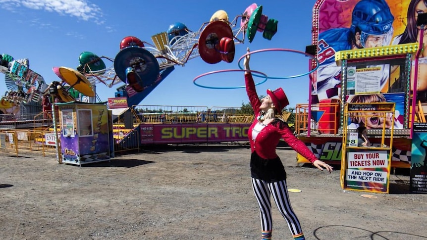 Woman in circus custom spinning two hula hoops above her head. 