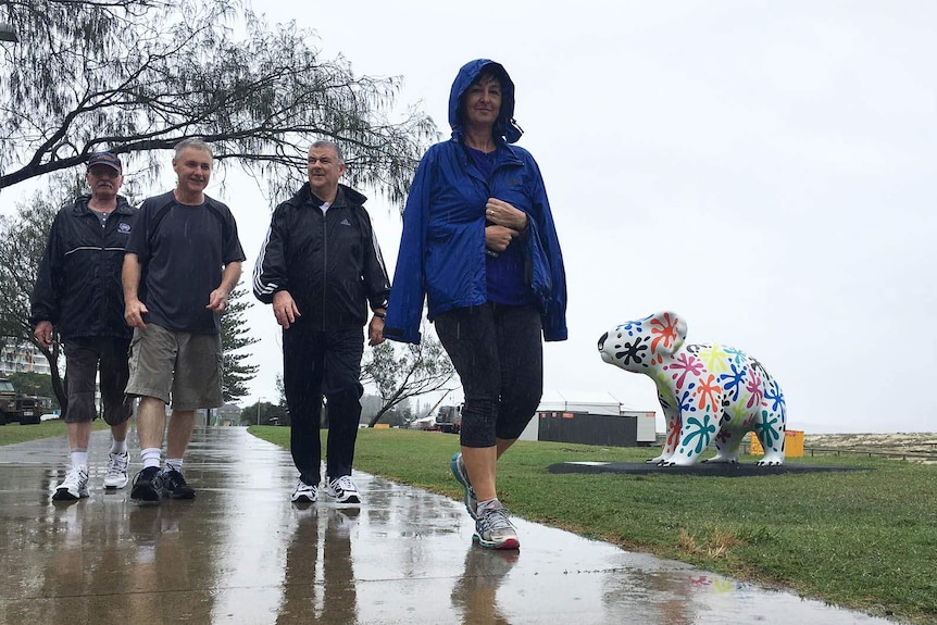 Kirra residents walk along the rain-drenched ocean front