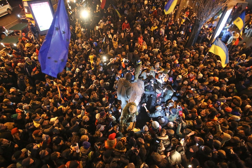 People surround a statue of Vladimir Lenin which was toppled by protesters in Kiev on December 8.