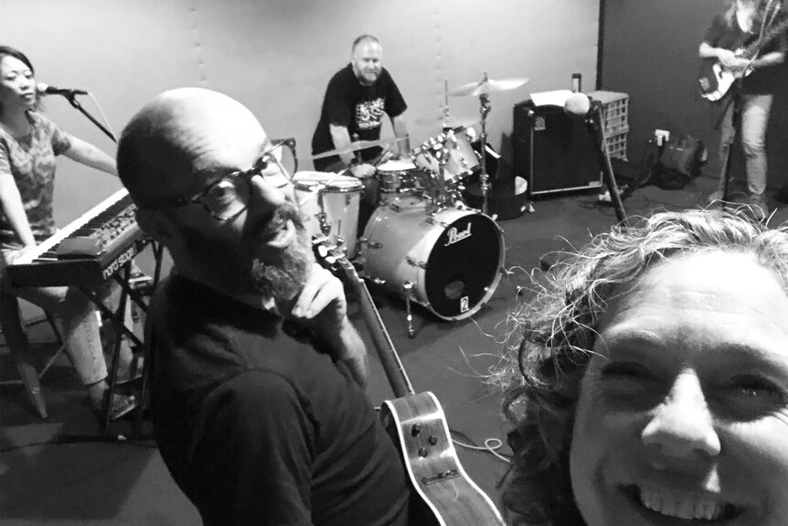 black and white photo of band frente at their instruments in a band rehearsal room