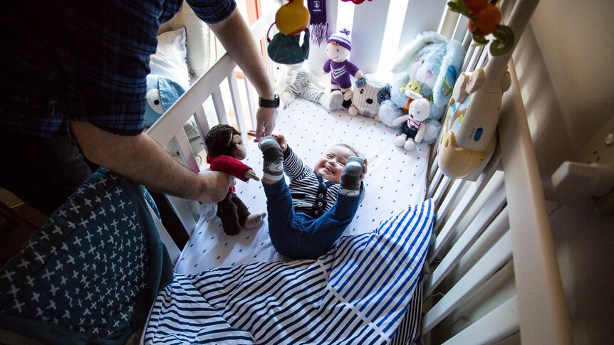 Baby Oskar playing with a monkey toy in a cot.