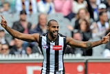 Heritier Lumumba smiles and celebrates with arms wide.