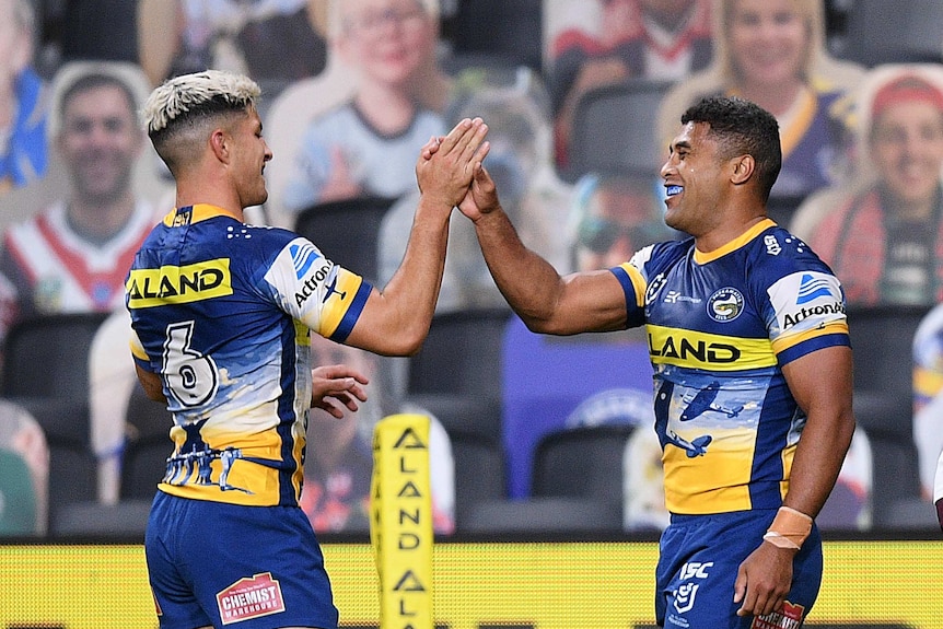 Two Parramatta NRL players high five each other as they celebrate a try scored against Manly.
