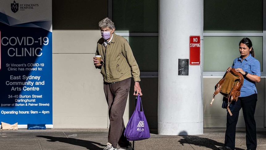 A man wearing a face mask and a woman walk outside of a Sydney hospital.