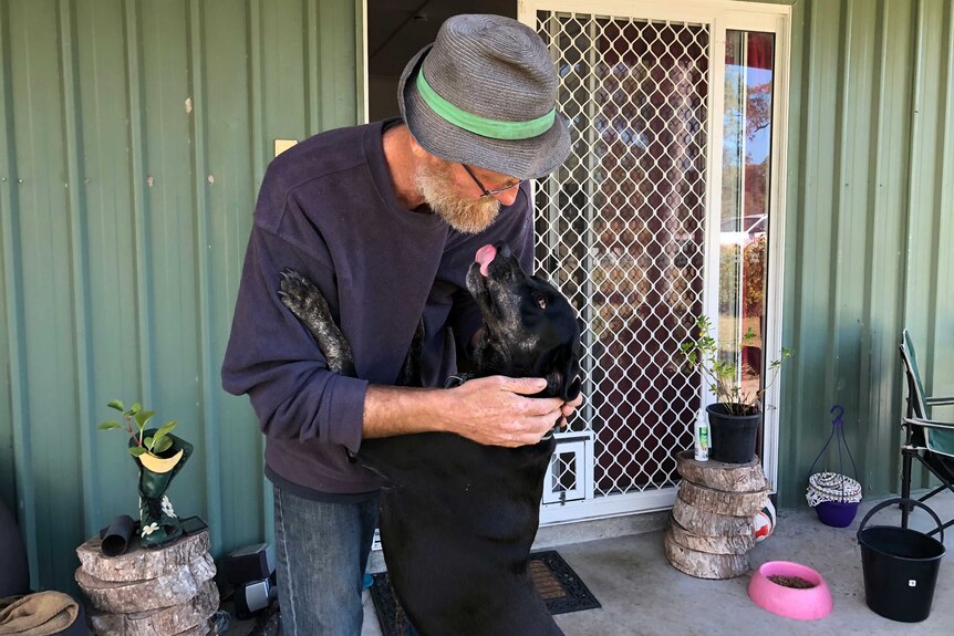 David Cook cuddles his dog outside at his home.