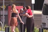 A group of people hug on a road